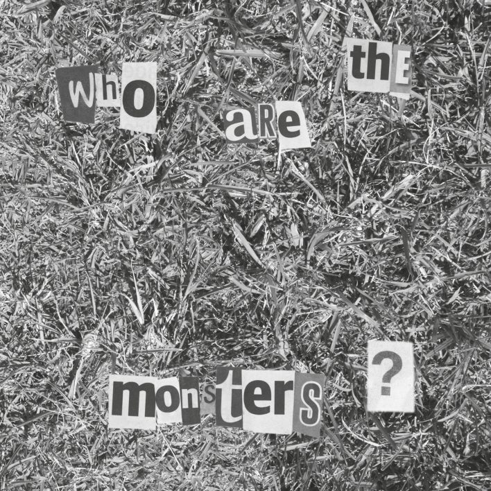 Black and white detail of grass with the words who are the monsters cut out of letters from newspapers ransom style.