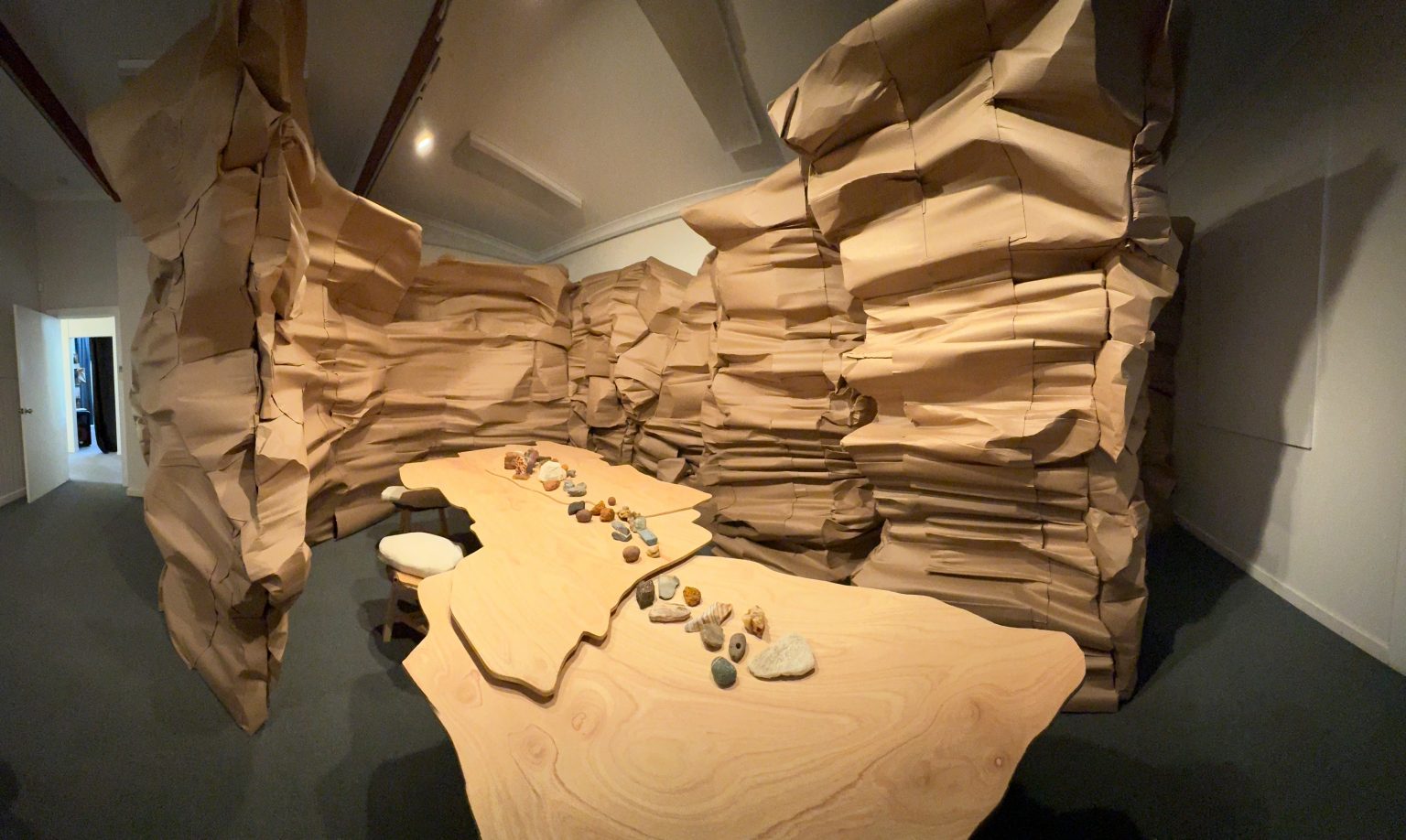 a dark room with a brown cardboard grotto. There are two irregularly shaped tables with a few rocks oon them