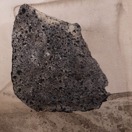 a dark black photogravure of a rock against a brownish background with a possible horizon towards the bottom of the image